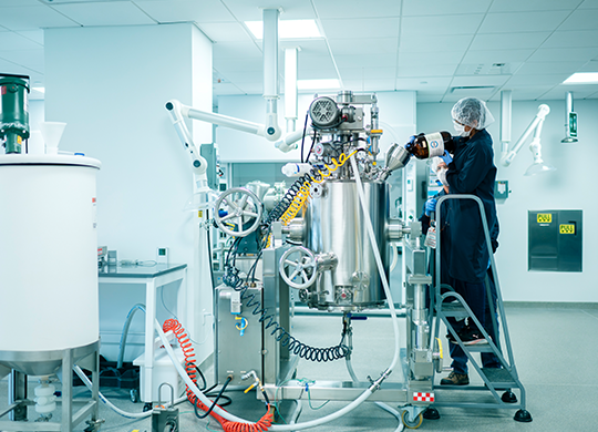 Technicians working with pilot plant large bioreactor. Technicians working with pilot plant large bioreactor.